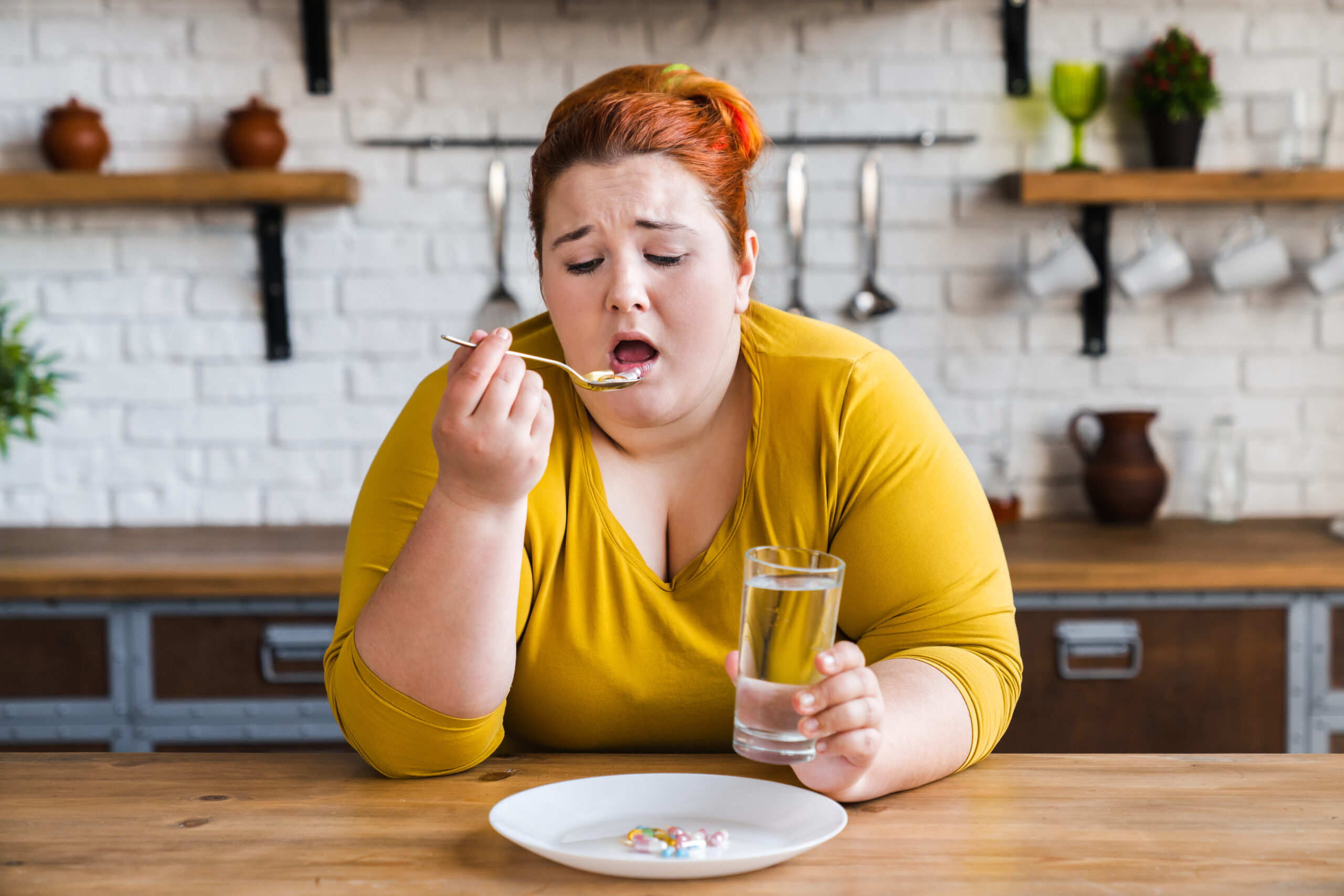 Obese young woman looking tired, and eating pills.
