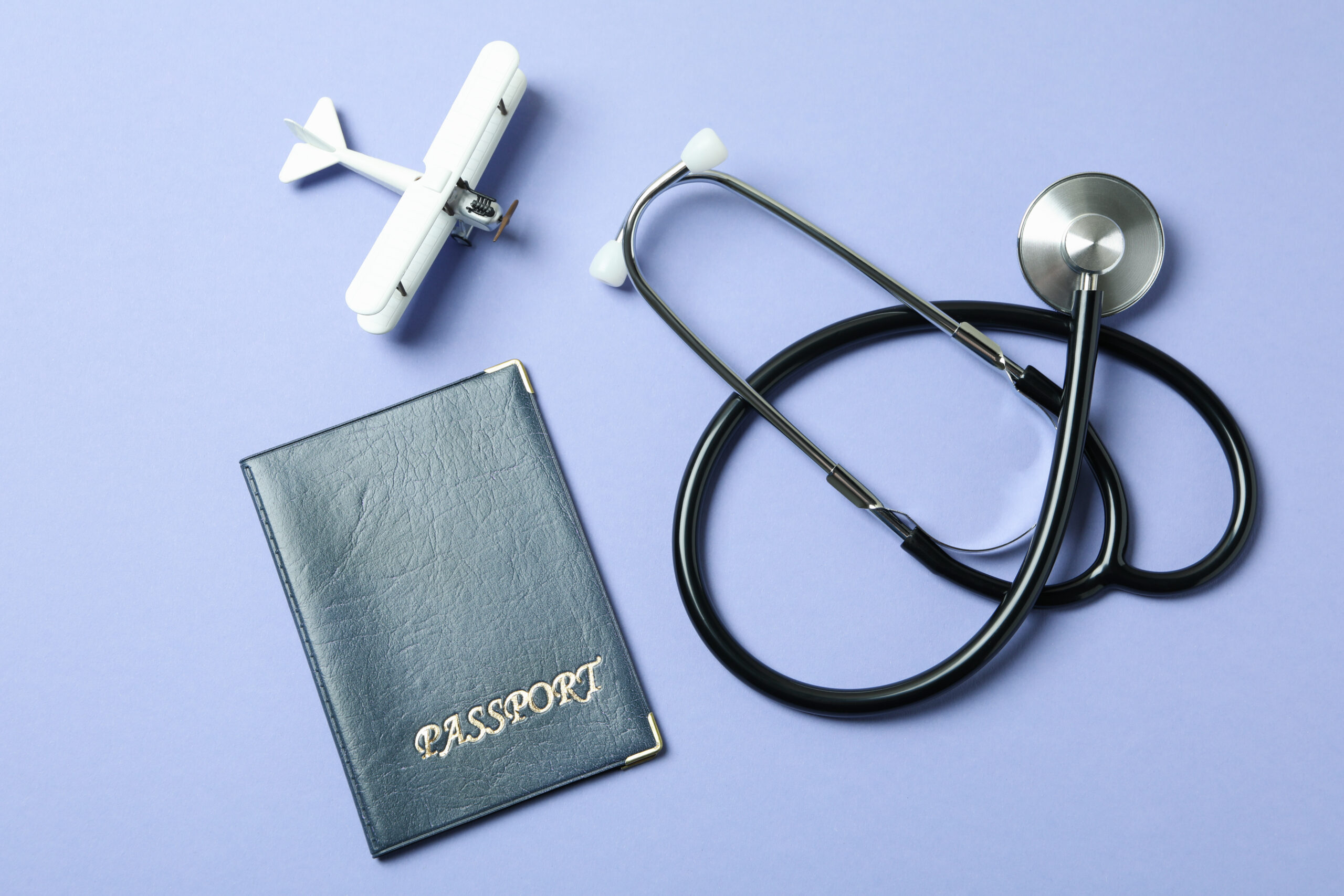 A passport, an airplane, and a stethoscope, representing medical tourism.