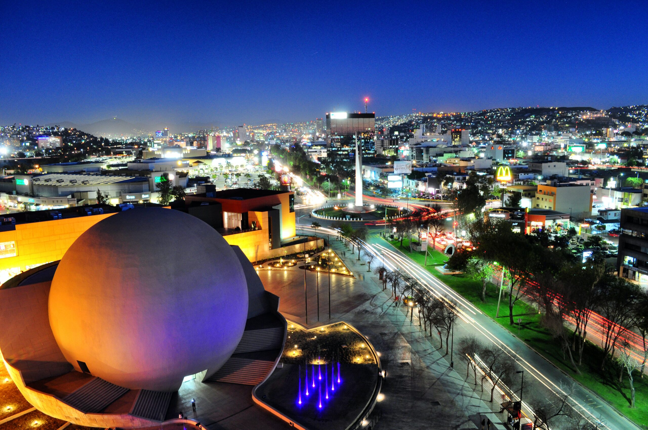 Tijuana, Mexico at night, with buildings, lights and the iconic bola movie theater.