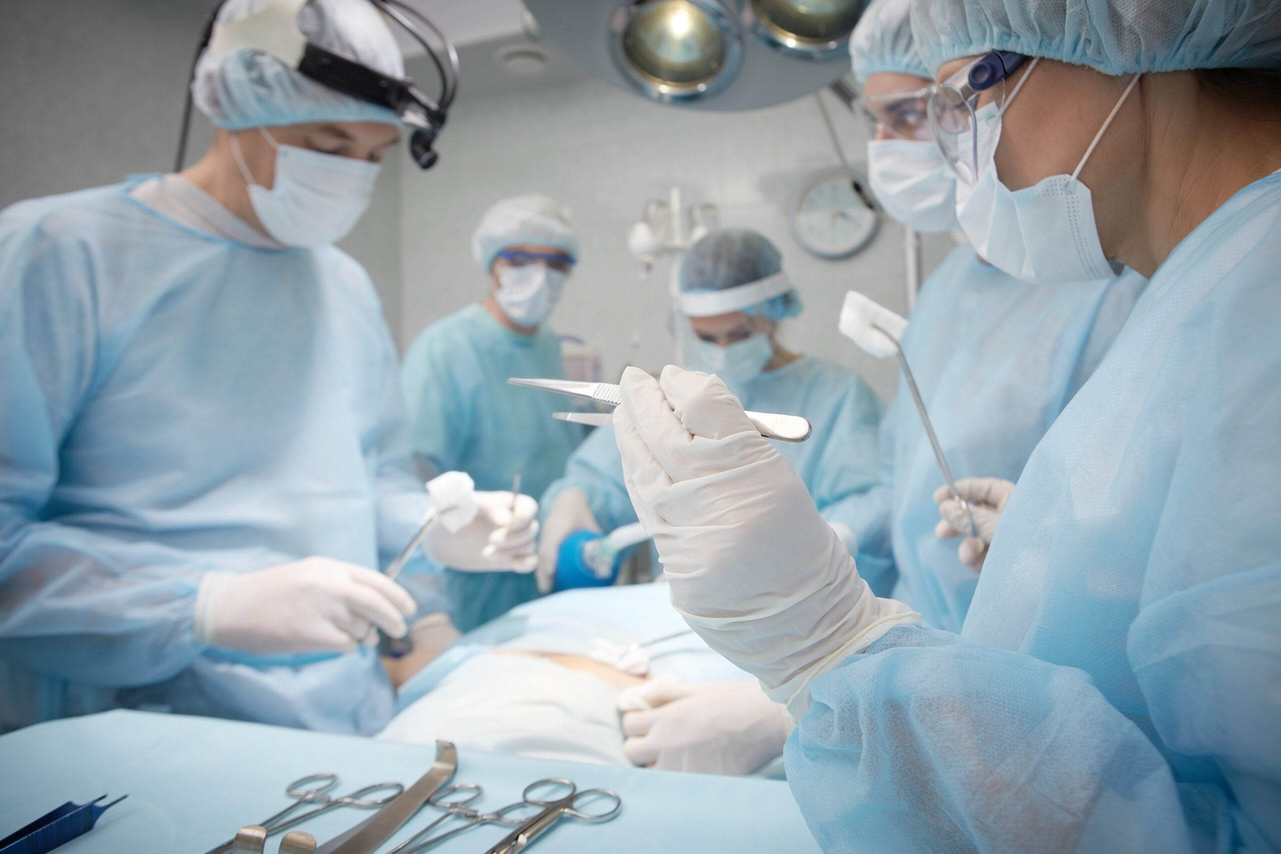 A team of surgeons holding surgical instruments and performing surgery.