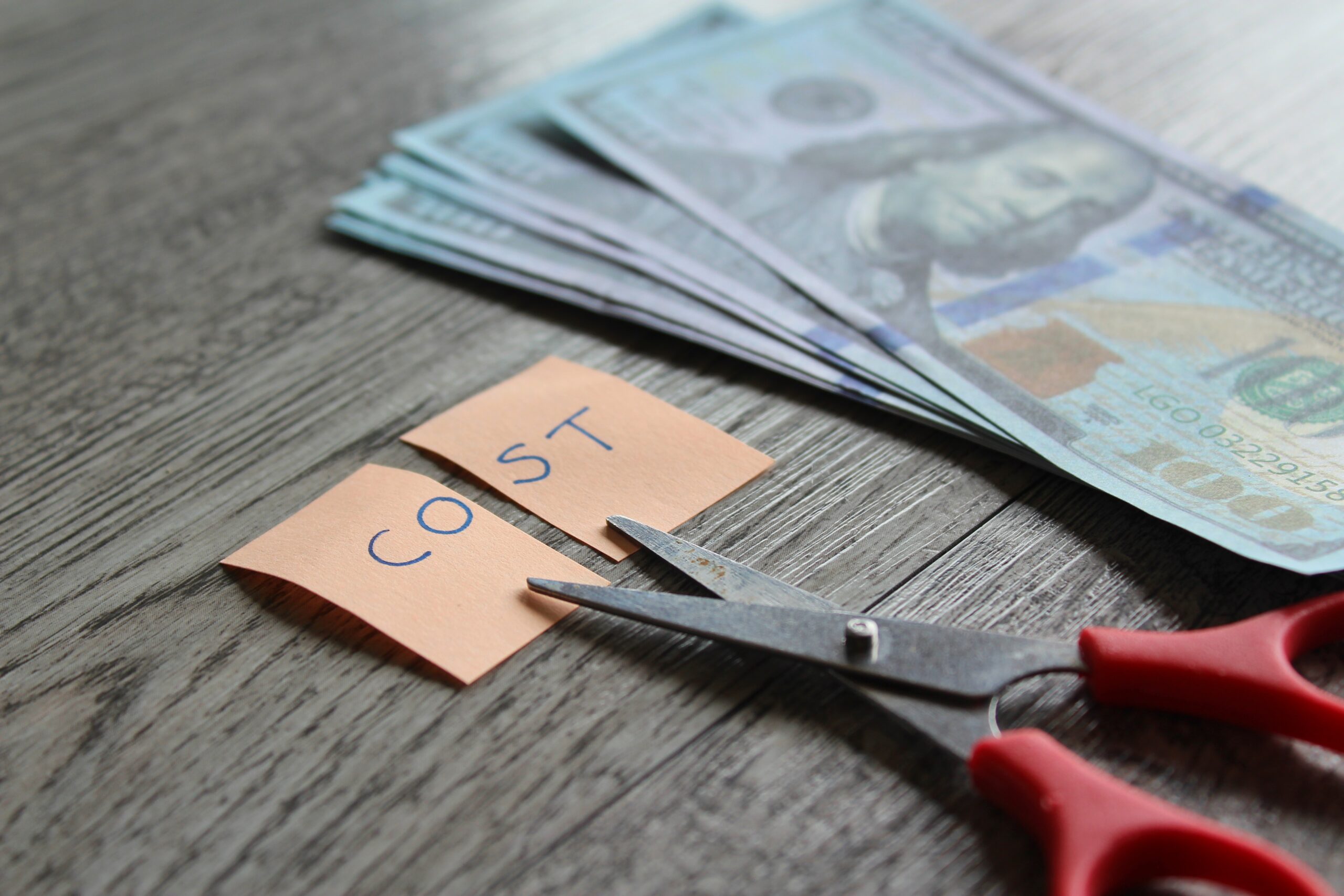 Scissor, money and note with text COST. Financial, cost cutting, 