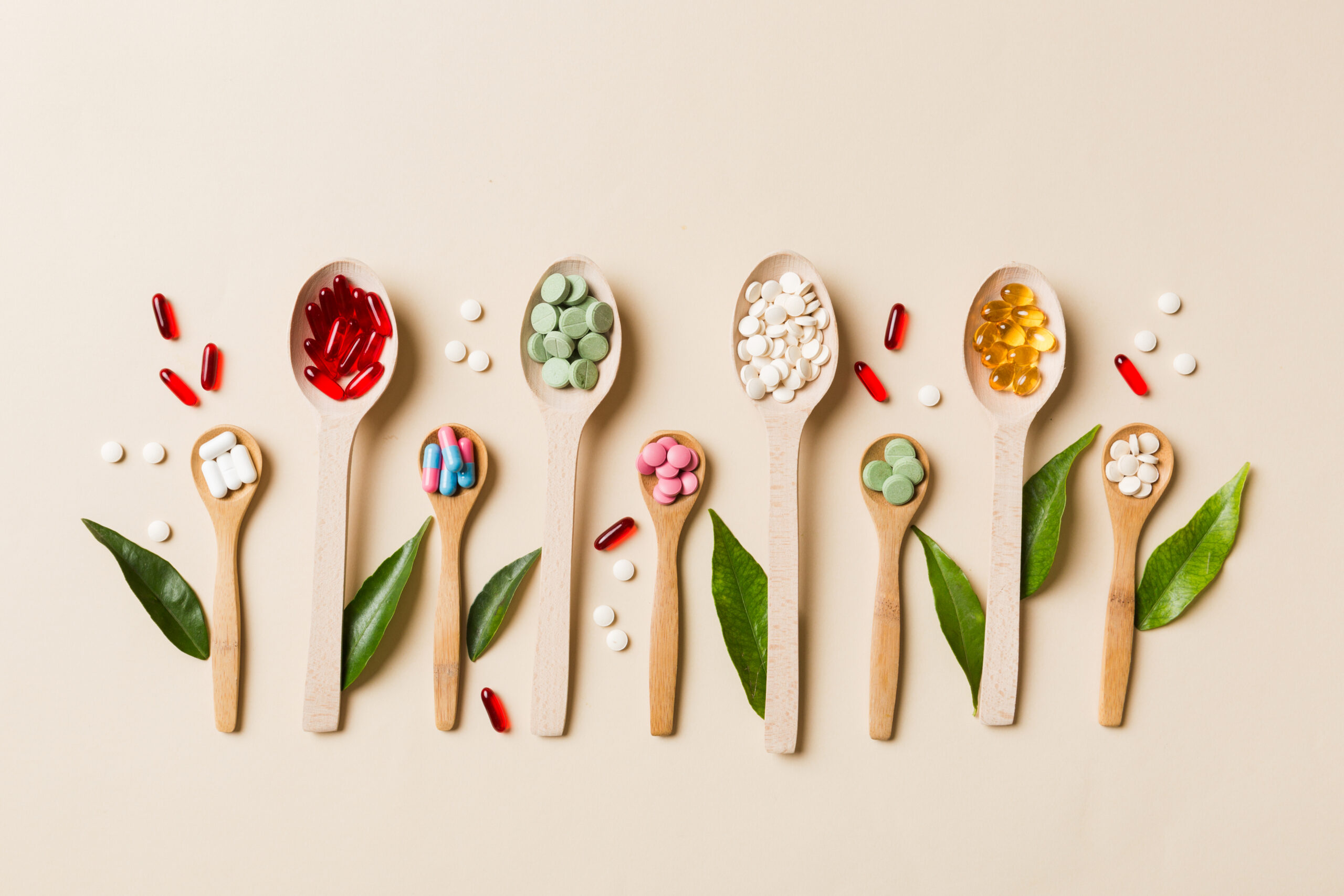 Top view Variety of vitamin and mineral pills in wooden spoon 