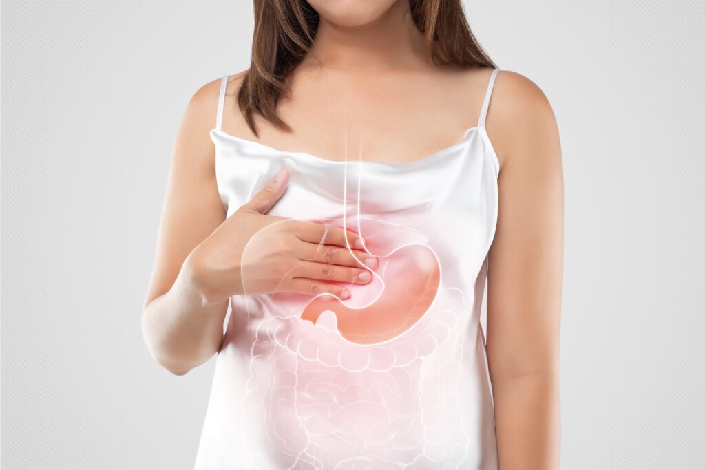 Woman touching her stomach and the illustration of the stomach can be seen.