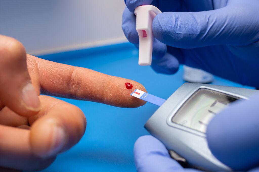 Gloved doctor holding a finger to take blood sample