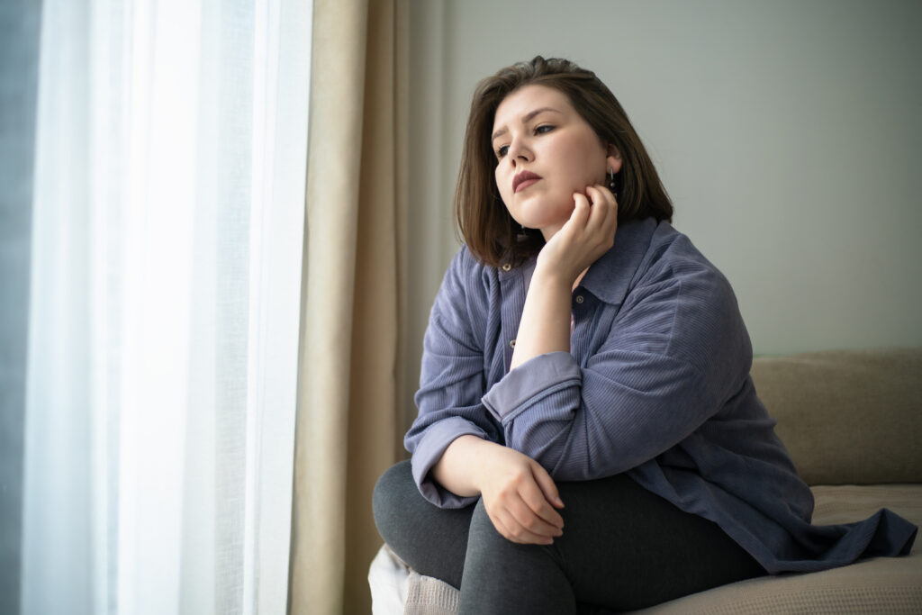 Plus size woman thinking while touching her chin.