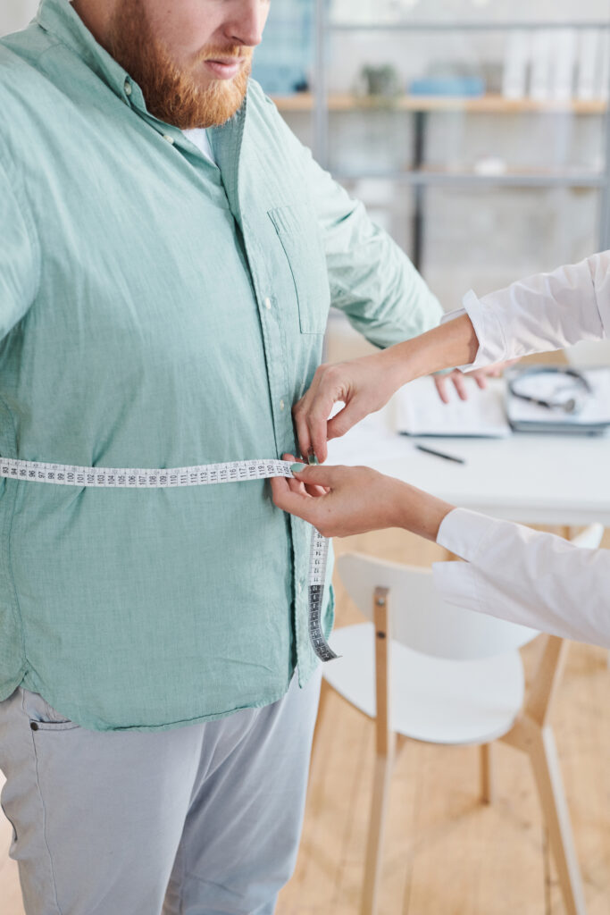 Overweight man being measured with a tape measure by a doctor