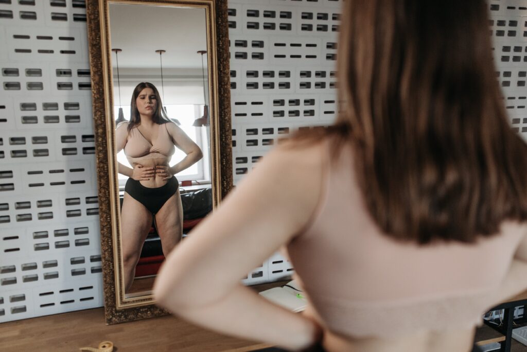Overweight woman looking at herself in the mirror.