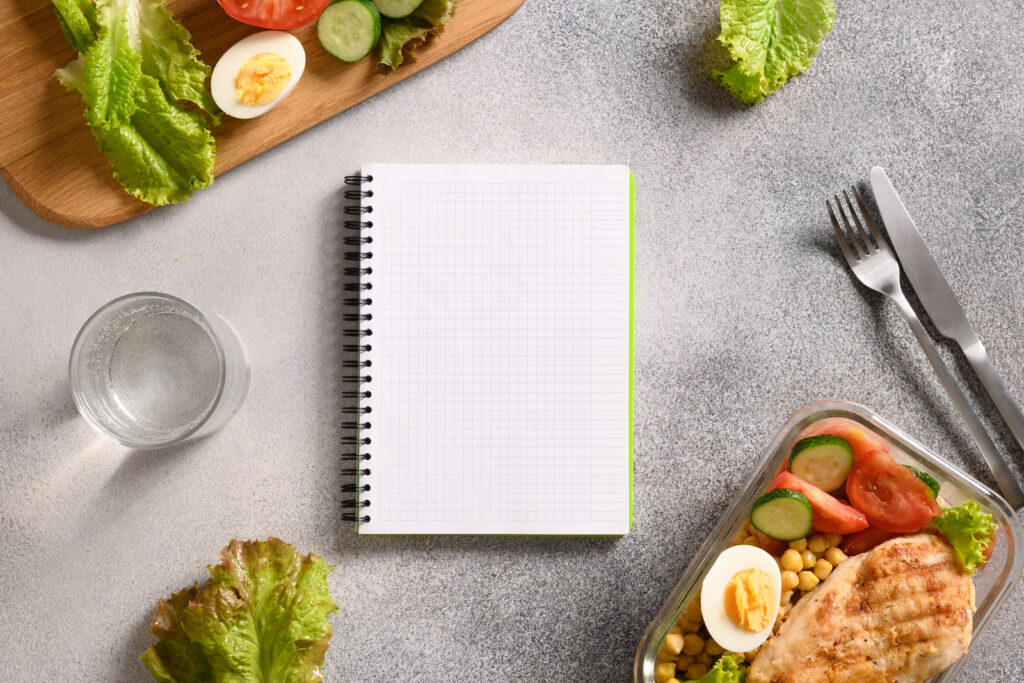 Weight loss concept, calories counting, diet, food control and calorie counter, diet plan. Notebook, food, salad, egg , water and vegetable.