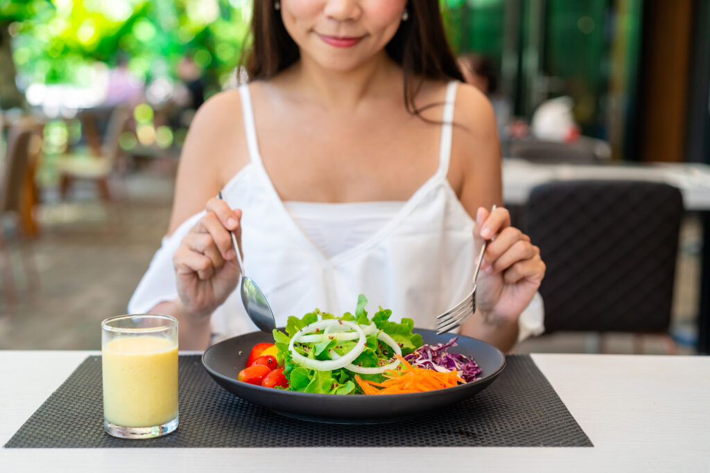 Woman eating a healthy salad at a restaurant.