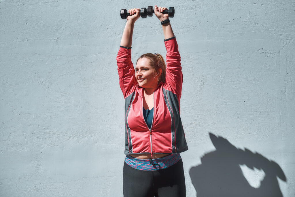 Woman lifting her arms and carrying weights.